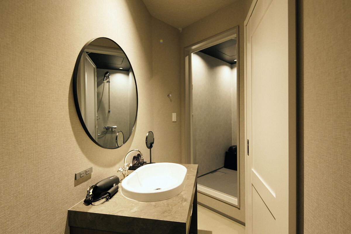 A bathroom with a round mirror, a sink, and a shower.