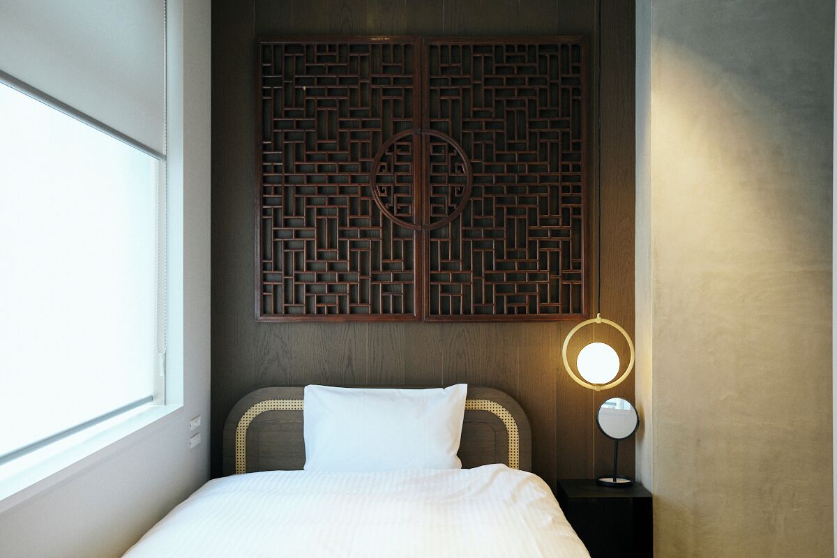 Ein Hotelzimmer mit Bett, Wanddeko, Nachttisch und Lampe sowie einem Fenster.
