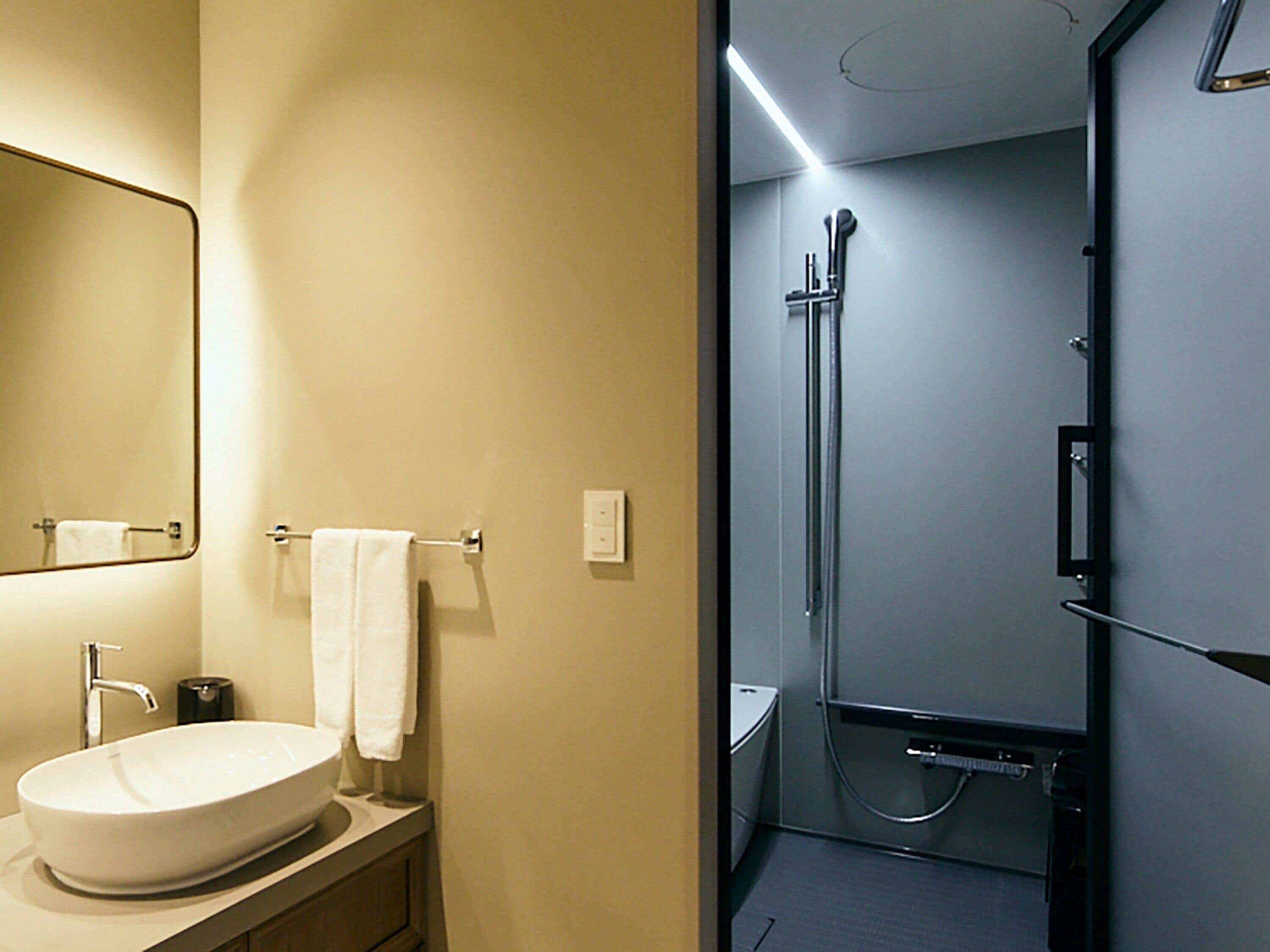 A bathroom with a sink, mirror, towel rack, and a shower area.