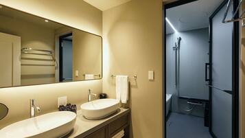 A modern bathroom with two sinks, a large mirror, and a shower area.