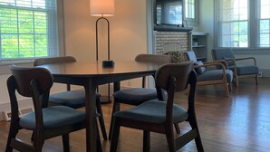 A dining area with a wooden table and chairs, a pendant light, and a view of a kitchen and living area through an archway. - Renovated In-Town Bungalow in French Lick (French Lick)