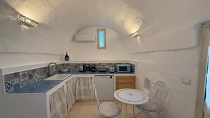 Une cuisine compacte avec un crédence carrelée, une petite fenêtre et un coin repas équipé de deux chaises.