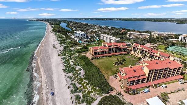 An aerial view of a coastal hotel with multiple buildings, a beach, and a river.