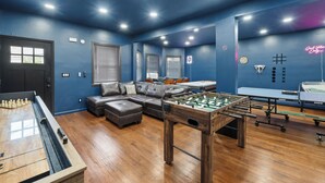 Une pièce équipée d’un baby-foot, d’une table de billard, d’un canapé et d’une table de ping-pong.