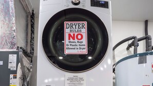 A stacked washer and dryer unit with a sign prohibiting shoes, rugs, or plastic items in the dryer. - Bohemia Villa  Heated Pool, Game Room & Playground 8 Adults 4 Kids Under 13 (Plantation)