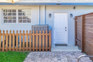 A house with a white door, a wooden fence, and an air conditioning unit.