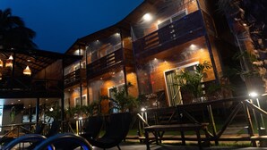 Un edificio de madera de varios pisos con balcones, mesas al aire libre y plantas en macetas.
