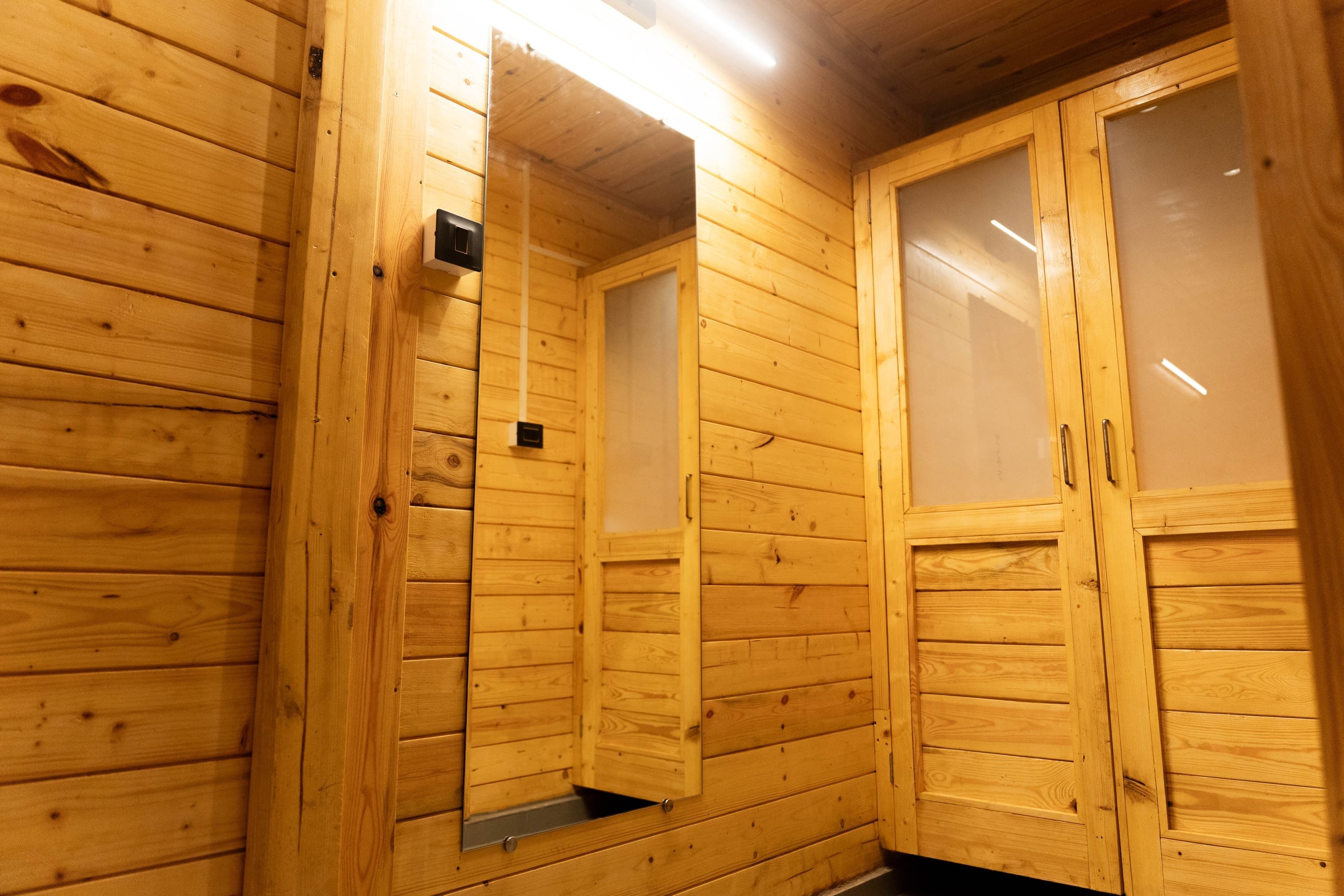 Ein Holzhäuschen im Inneren, mit einer Holztür, einem kleinen Fenster und einer Lampe.