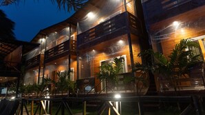 Un edificio de madera de varios pisos con balcones, rodeado de palmeras.