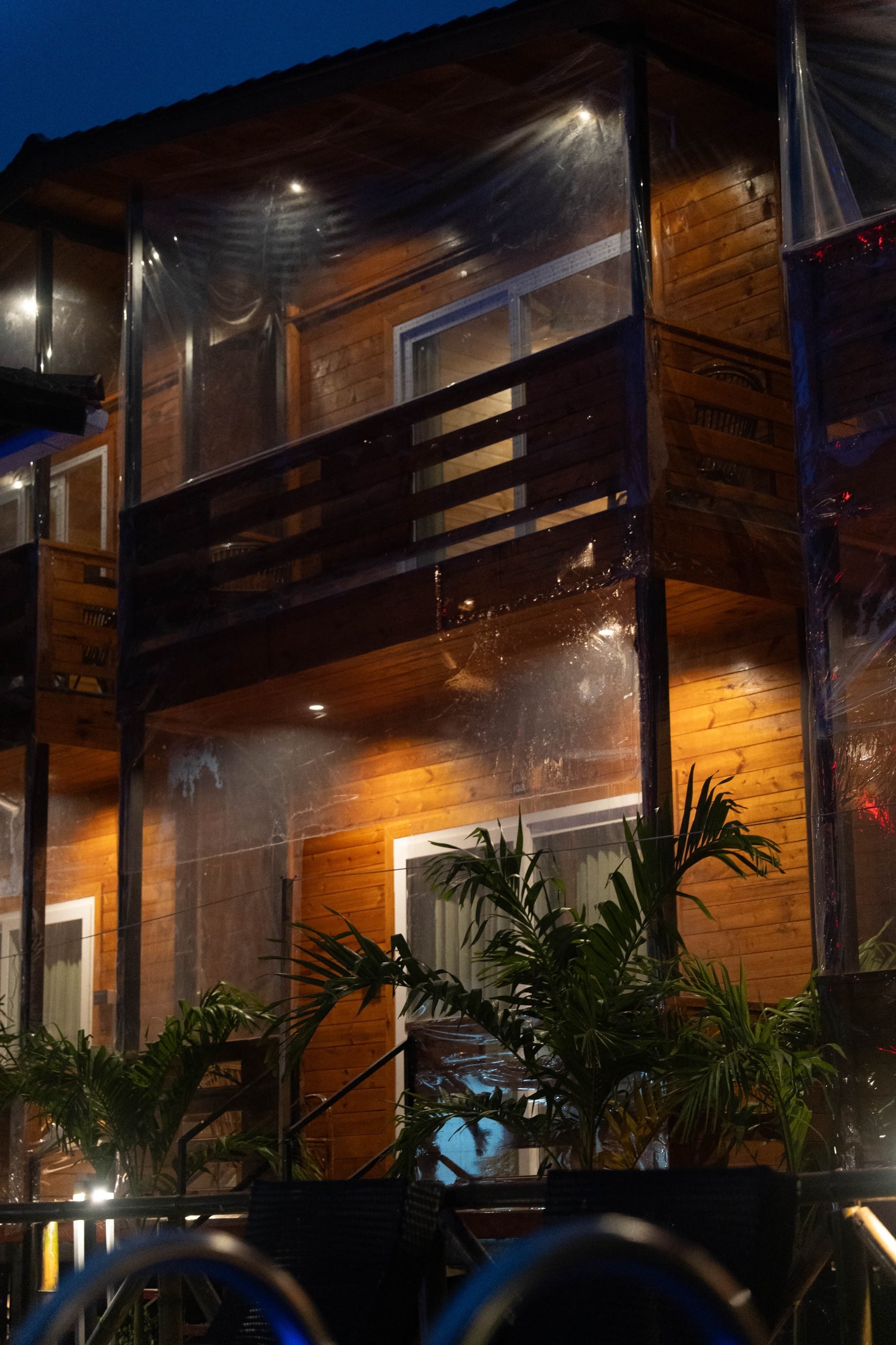 A wooden building with a glass facade, potted plants, and a staircase.