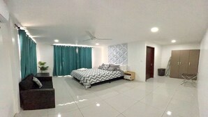 Une chambre moderne comprenant un lit, une table de chevet, un ventilateur de plafond, une armoire et un coin salon.