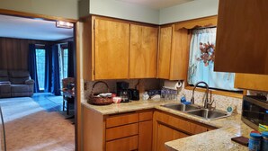 A compact kitchen with wooden cabinets, a granite countertop, a built-in microwave, and a sink. - Woodland Retreat in Spokane / Mead (Mead)