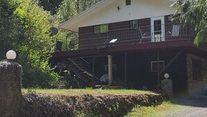 A two-story building with a balcony, surrounded by trees. - Woodland Retreat in Spokane / Mead (Mead)
