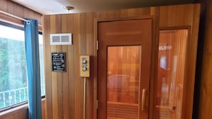 A wooden-paneled room with a sauna, a control panel, and a window with curtains. - Woodland Retreat in Spokane / Mead (Mead)