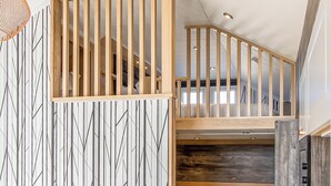 A modern interior with a wooden staircase, a geometric wall pattern, and a dark wood panel. - Pladda Pod with Hot Tub S (Ayr)