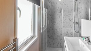 A modern bathroom with a shower, a sink, and a window. - Pladda Pod with Hot Tub S (Ayr)