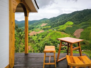 Una terraza de madera con una mesa y sillas que da a un valle exuberante.