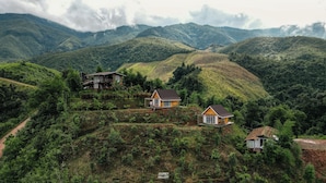 A mountainous landscape with three houses surrounded by lush greenery. - Baan Klangkao (Bo Kluea)