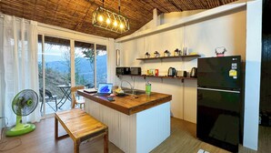 A kitchen with a wooden island, a built-in refrigerator, and a dining area with a bench. - Baan Klangkao (Bo Kluea)