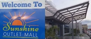Een bord van Sunshine Outlet Mall met een zongrafiek en de tekst 'Welcome To Sunshine Outlet Mall'.