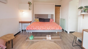 Un dormitorio con cama, mesitas de noche, un escritorio y una silla.