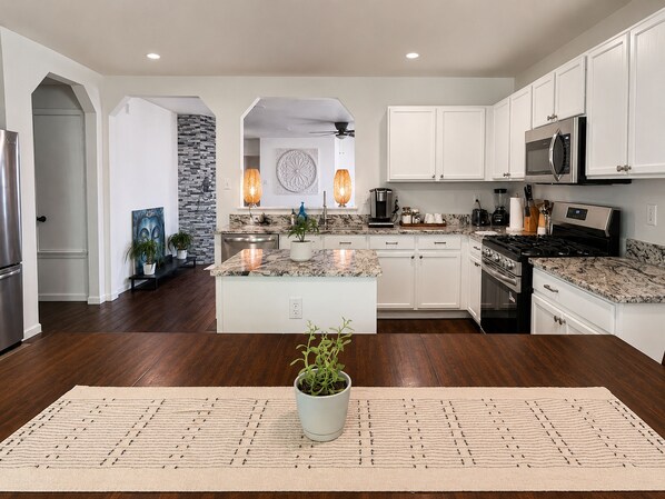 A modern kitchen with white cabinetry, a central island, and a stone accent wall.