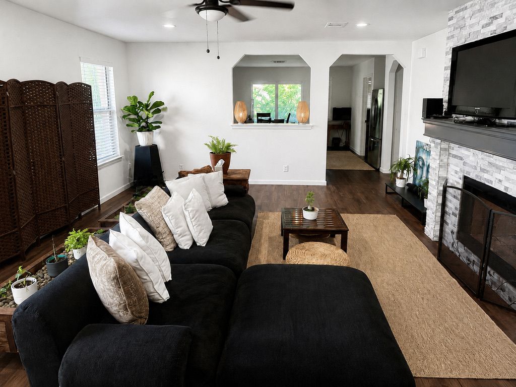 A modern living room with a black sofa, a fireplace, and a television.