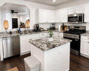 A modern kitchen with white cabinetry, stainless steel appliances, and a marble countertop. - THE ZEN LUXE LOUNGE (Cedar Park)