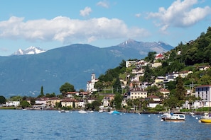 Eine Küstenstadt mit Gebäuden an einem Hügel, Booten auf dem Wasser und Bergen im Hintergrund.