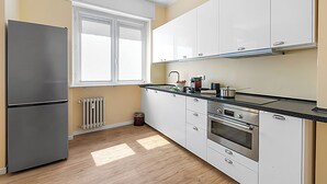 A kitchen with a refrigerator, oven, and cabinets.