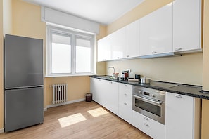 A kitchen with a refrigerator, oven, and cabinets.