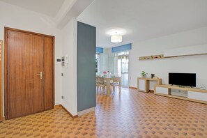 A spacious living area with a wooden door, a dining table with chairs, a flat-screen TV, and a patterned floor. - Diana & Mark family house, Vobarno, Italy (Vobarno)