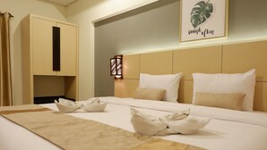 Una habitación de hotel con una cama grande, cabecera con lámpara y una obra de arte colgada en la pared.