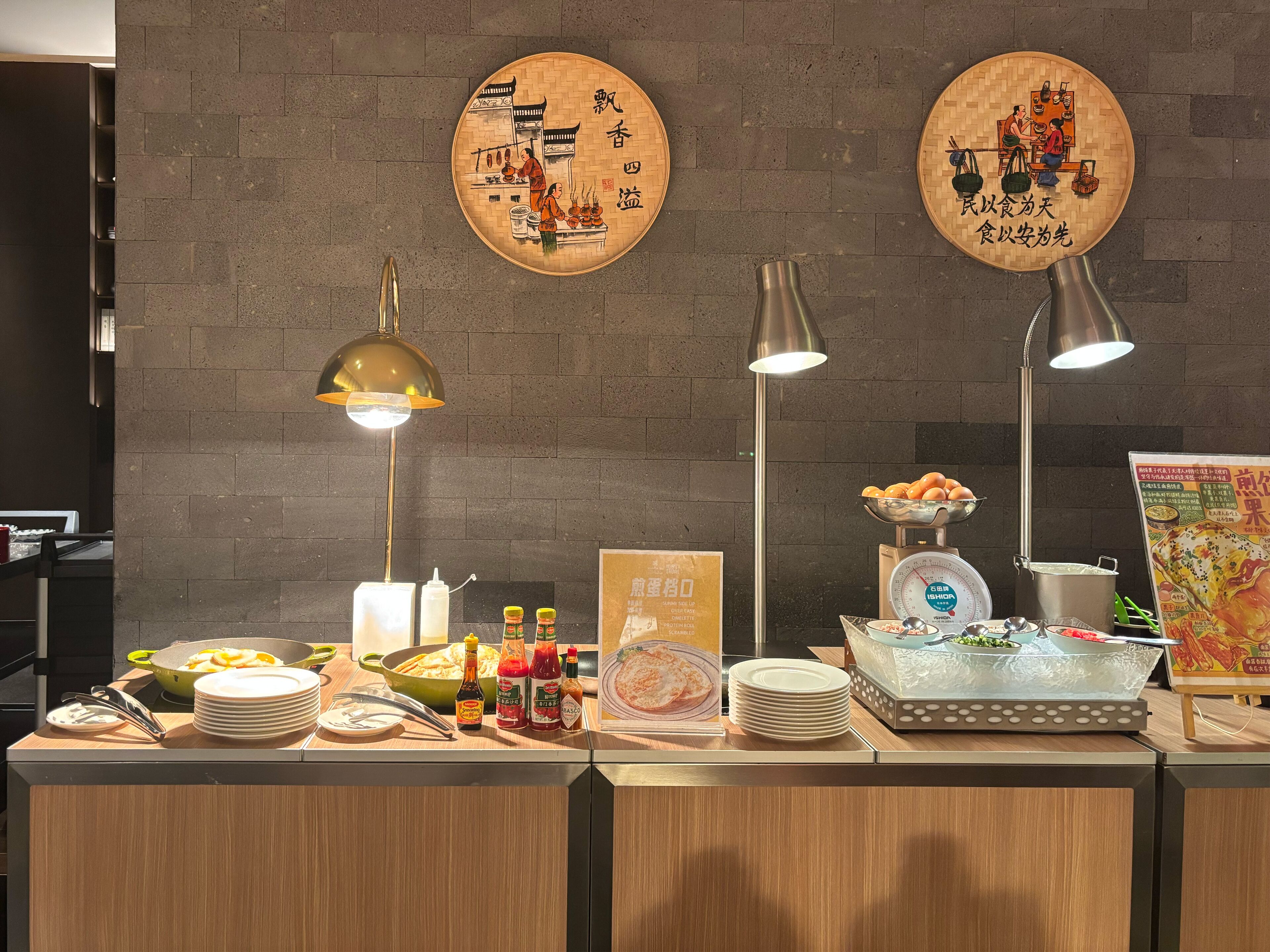 Una barra de buffet con diferentes alimentos, salsas y un panel con el menú.