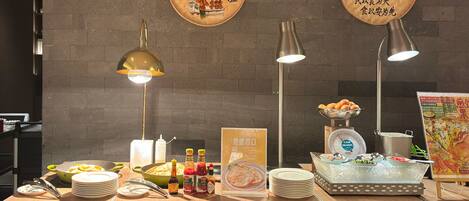 Una barra de buffet con diferentes alimentos, salsas y un panel con el menú.