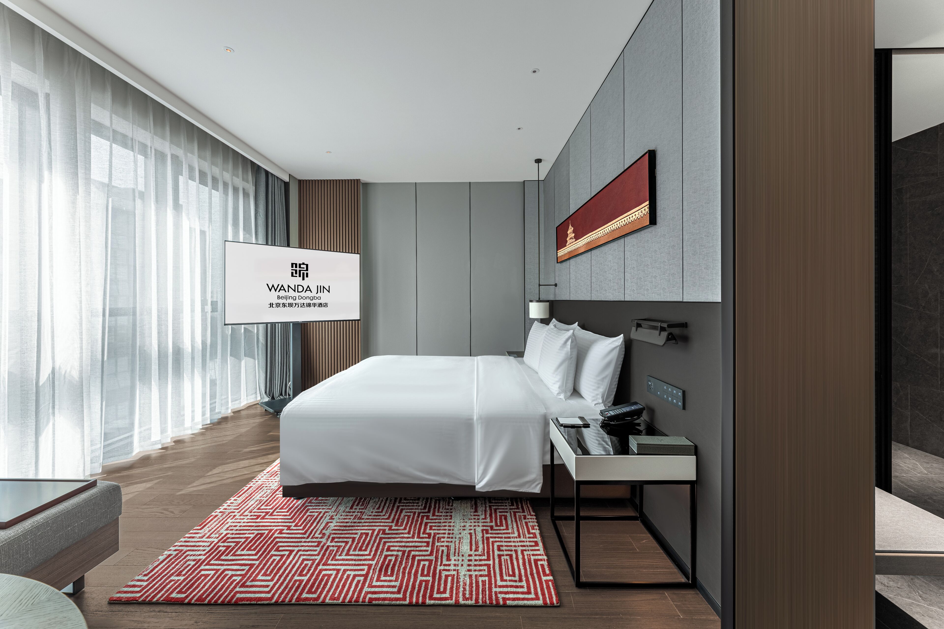Een moderne hotelkamer met een groot bed, een bureau met telefoon en een tv aan de muur.