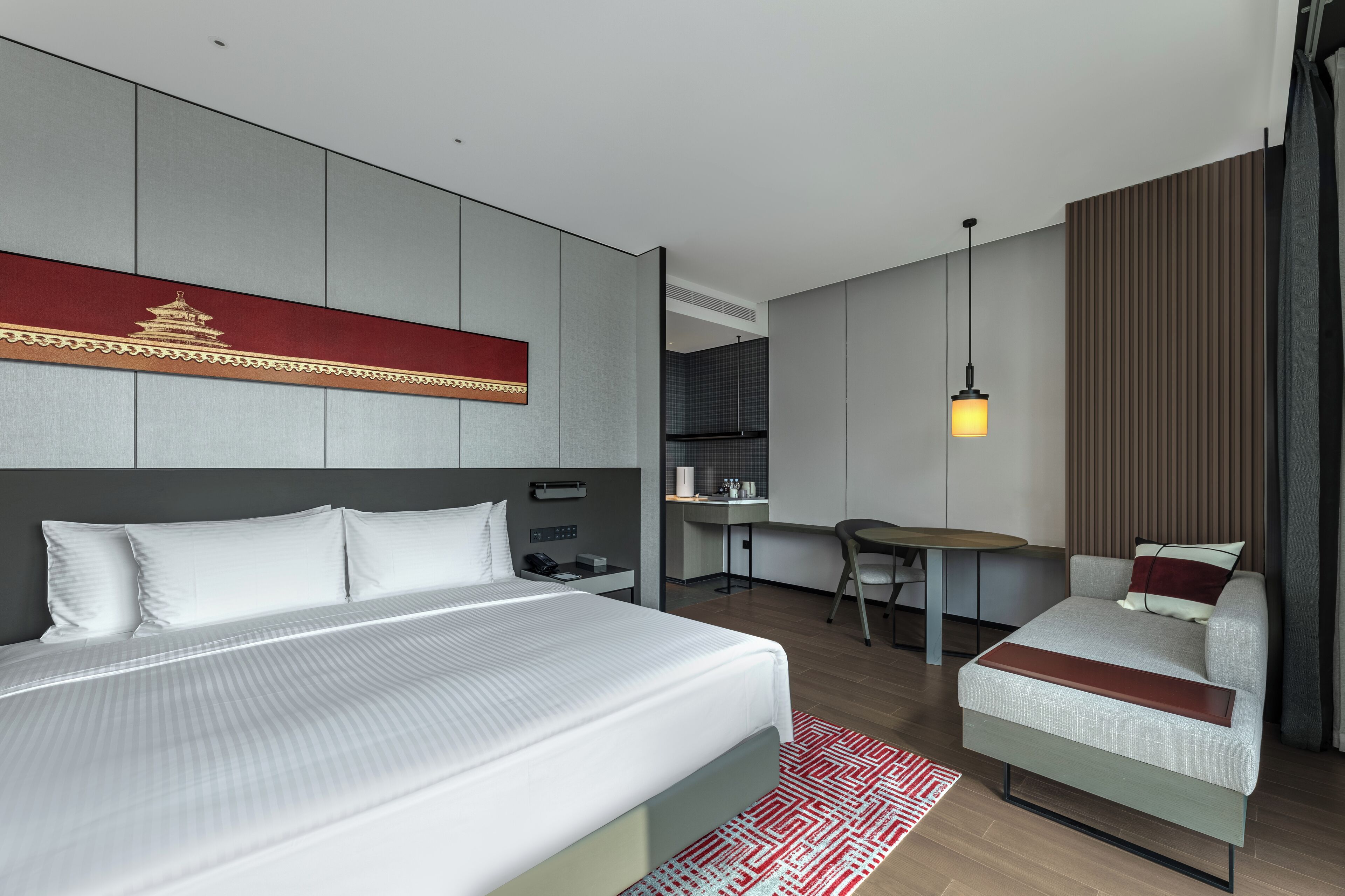 A modern hotel room with a large bed, a desk, and a small sofa.