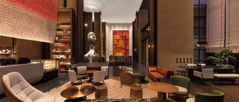 A modern lobby with a central seating area, a reception desk, and a decorative wall with a large artwork.