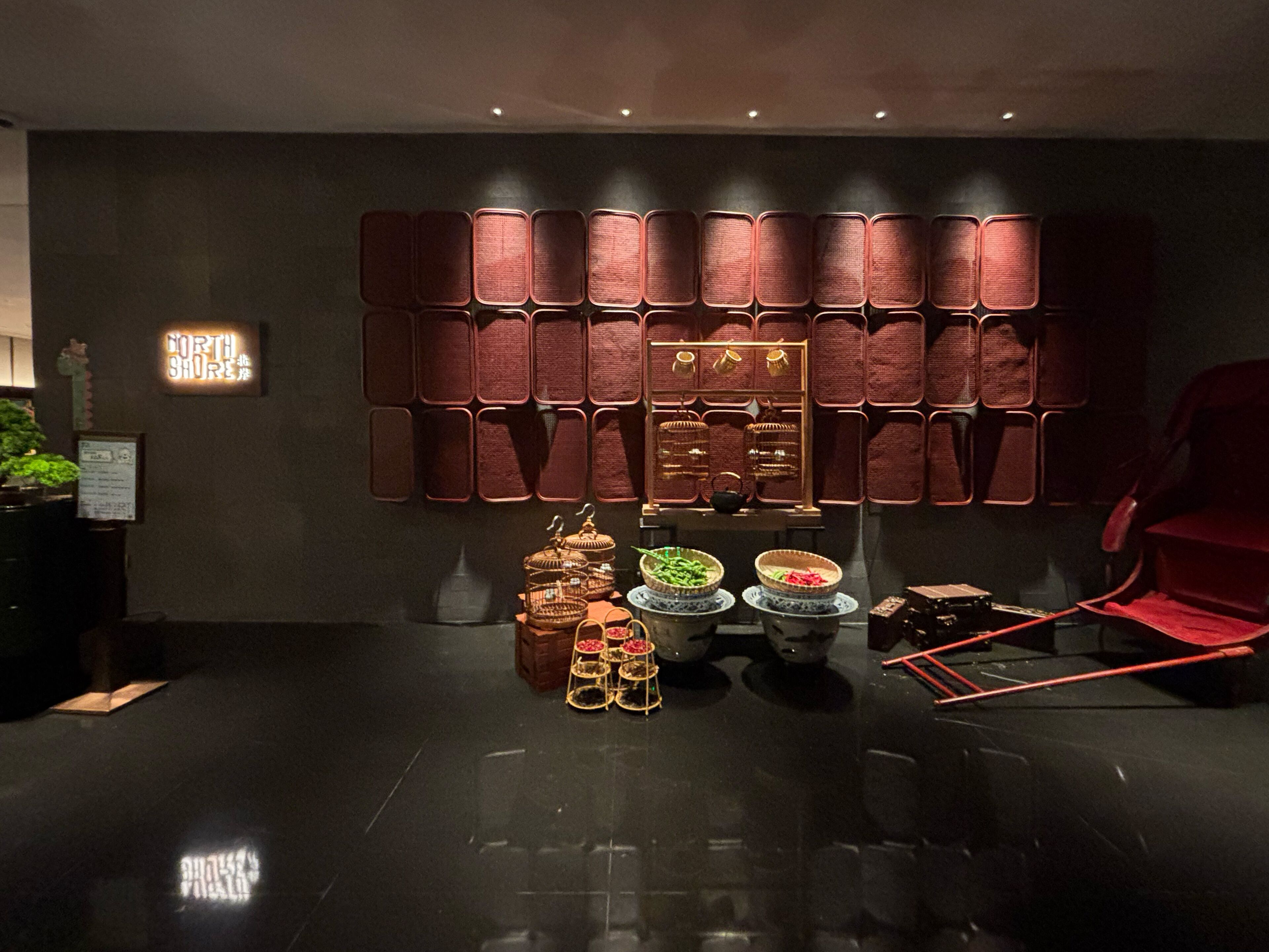 Un interior moderno con piso oscuro, una silla roja y una pared con varios compartimentos.