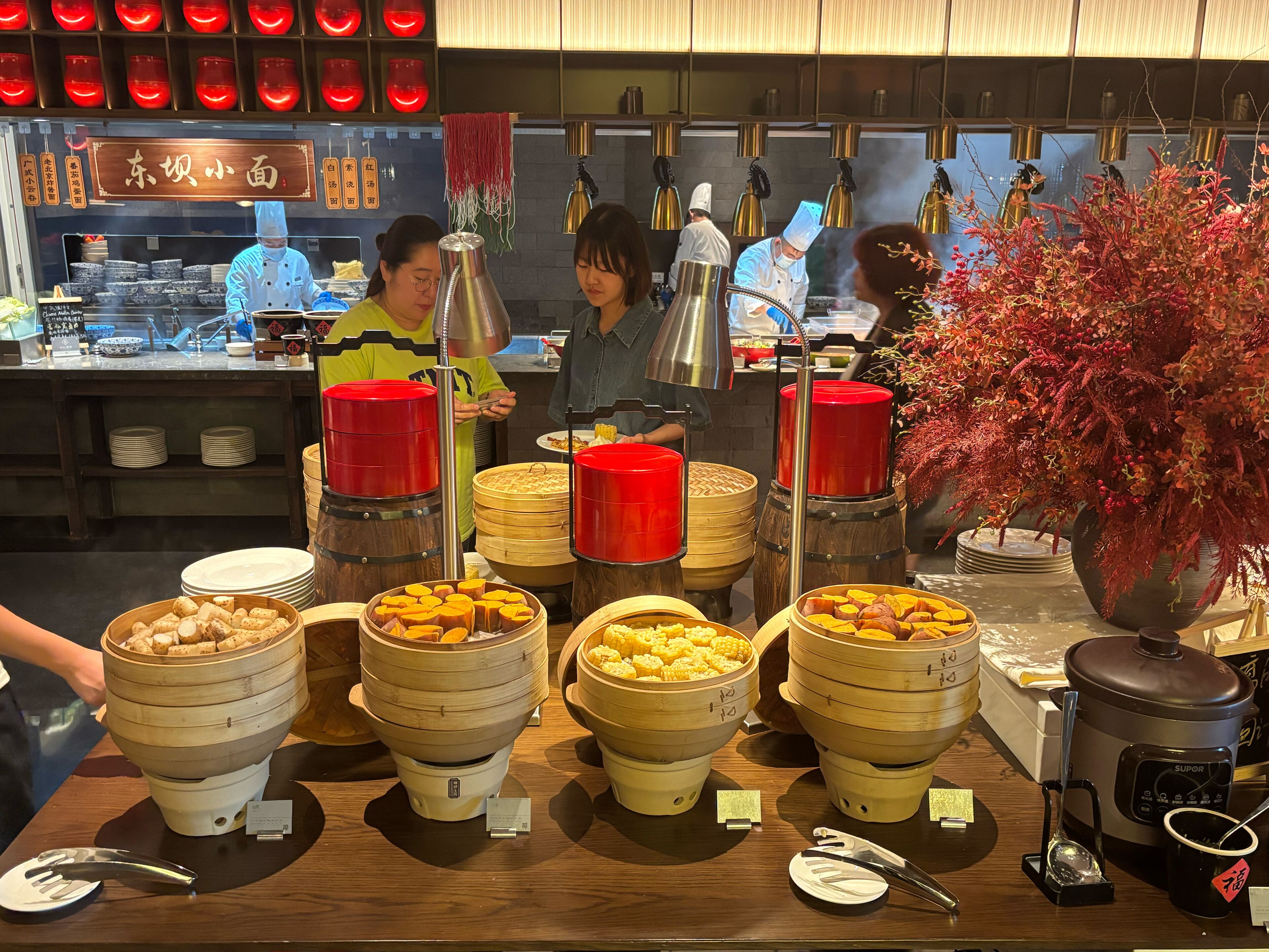 A buffet setup with multiple food stations, including bamboo steamers and a slow cooker.
