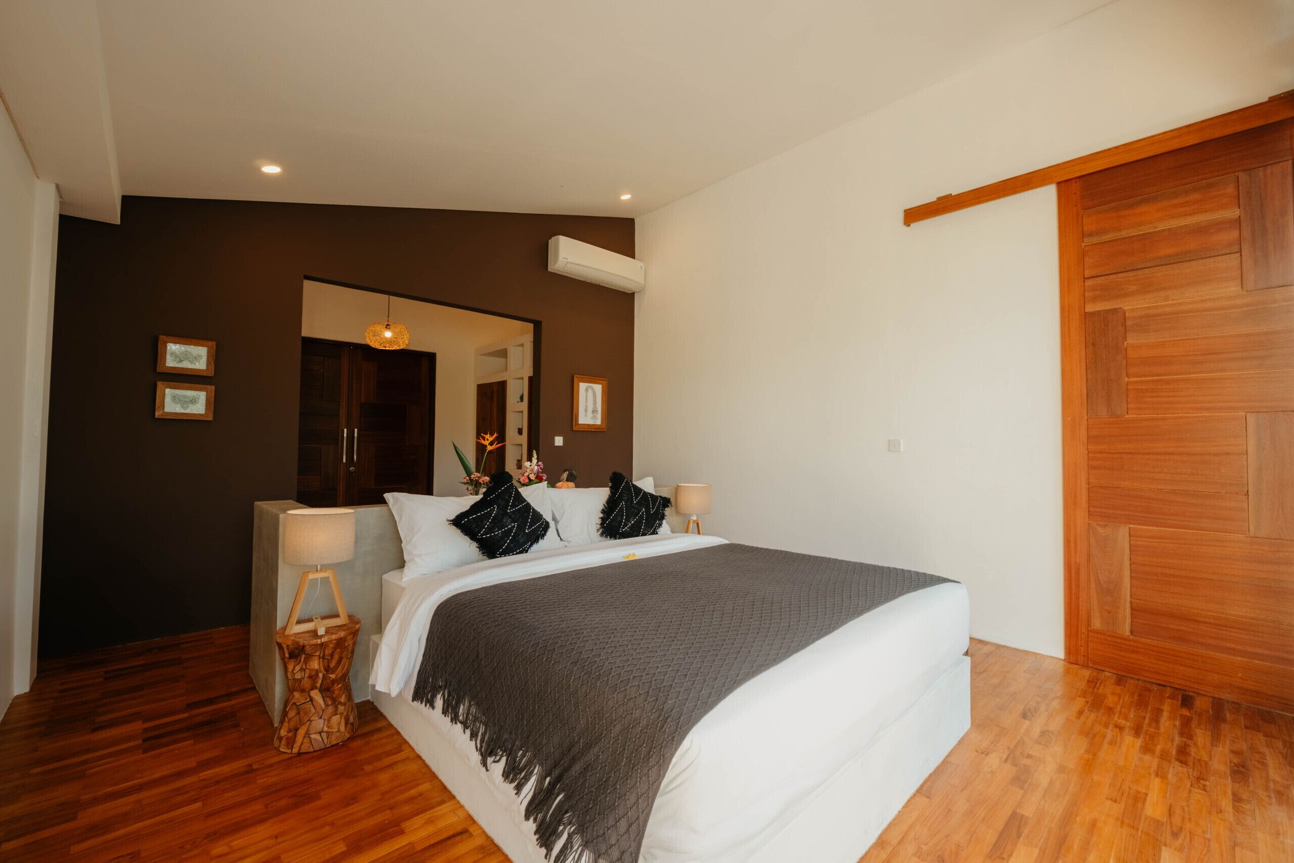 Una camera da letto con un letto grande, pavimento in legno, uno specchio e una porta in legno.