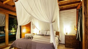 A spacious bedroom with a large bed, a canopy, wooden walls, and a view of a pool.