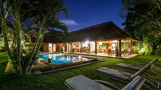 A poolside area with lounge chairs, a swimming pool, and a covered outdoor seating area.