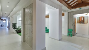 A spacious hallway with white walls, a wooden ceiling, and a green chair near a door. - Hidden Hill Bulguksa Hotel (Gyeongju)