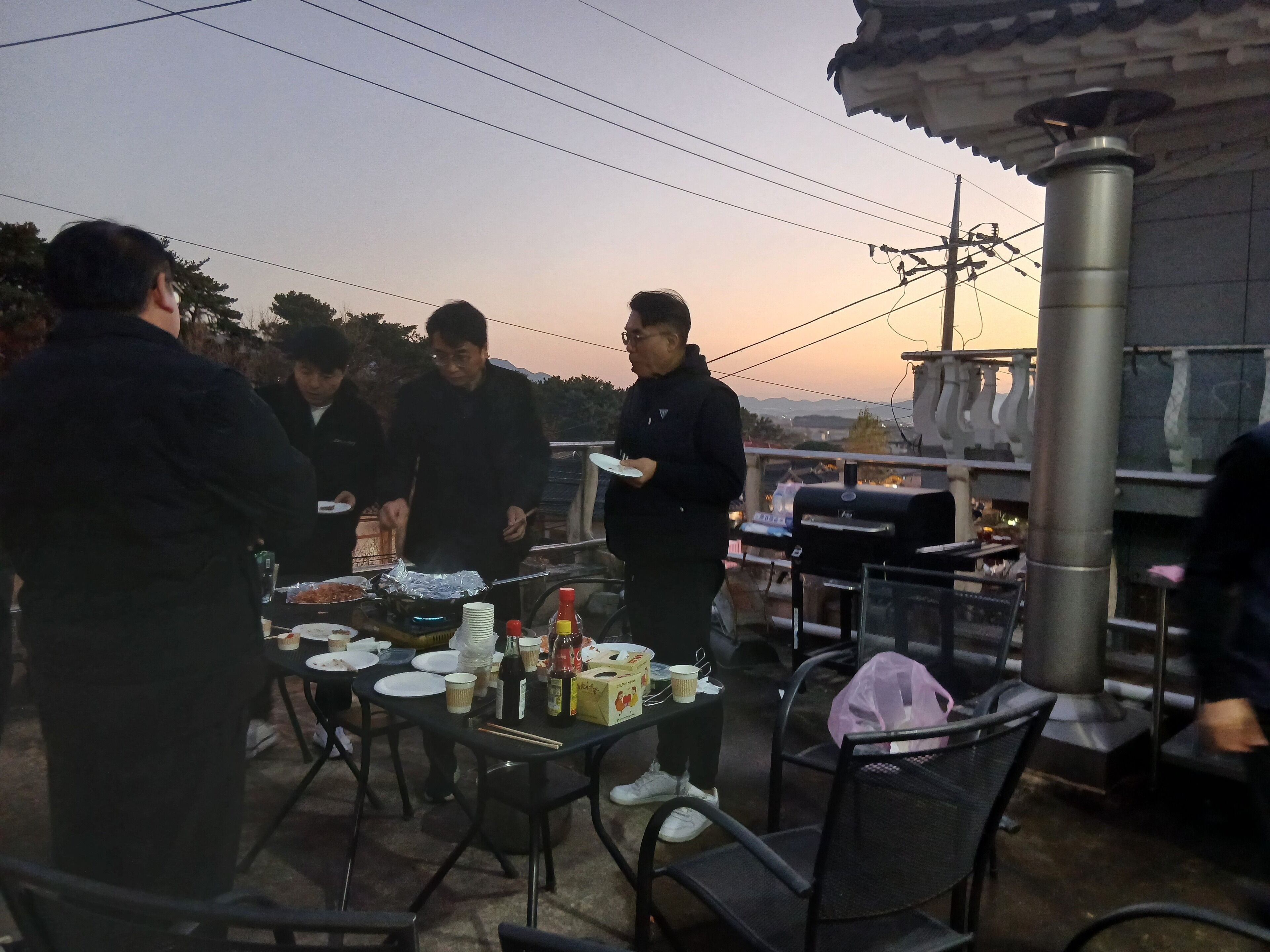 A group of people dining outdoors at a table with various dishes and condiments.