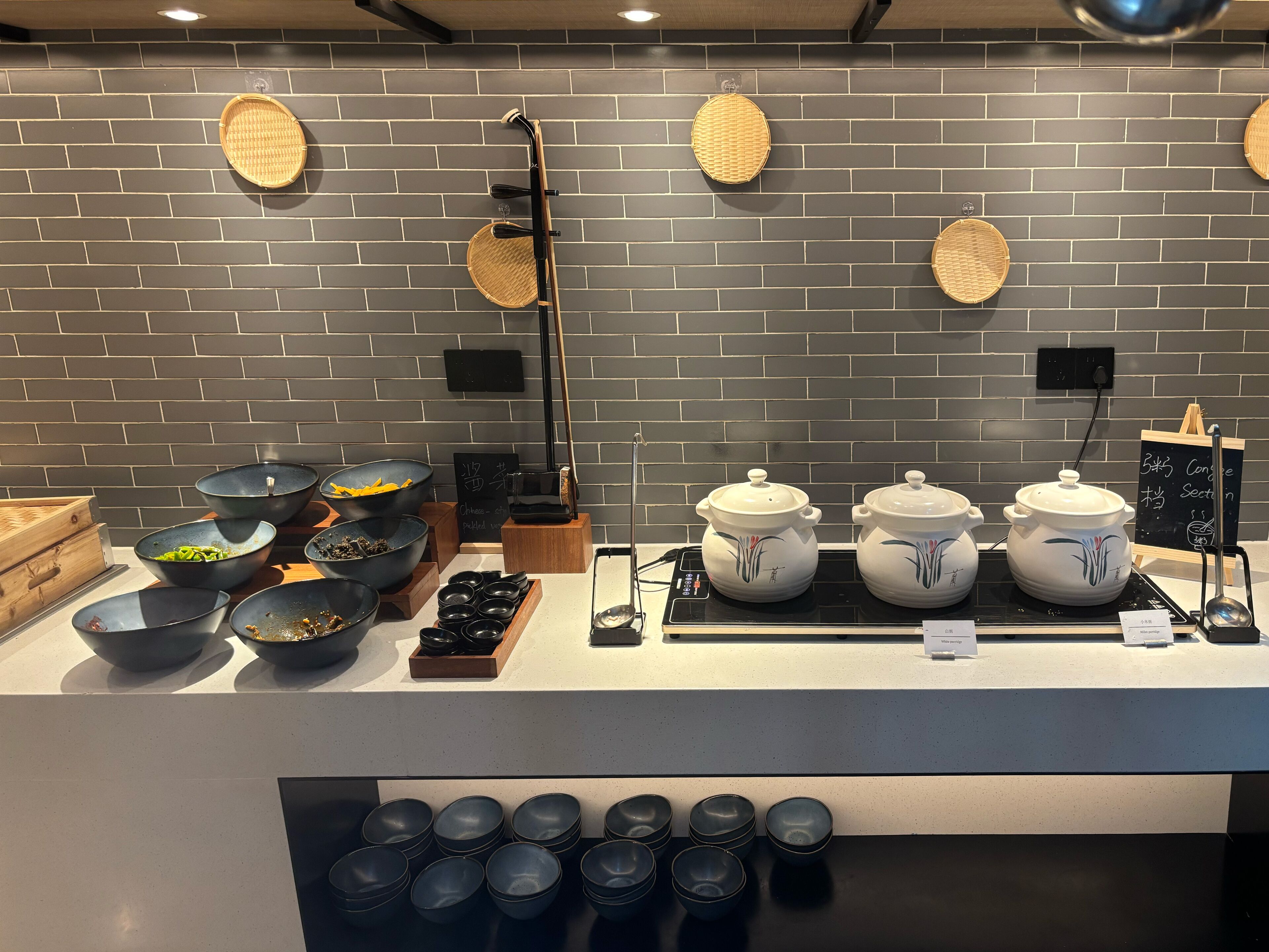 A kitchen counter with various cooking utensils, bowls, and pots.