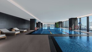 A modern indoor pool with lounge chairs and a city view. - Beijing Dongba Wanda Moments hotel (Beijing)