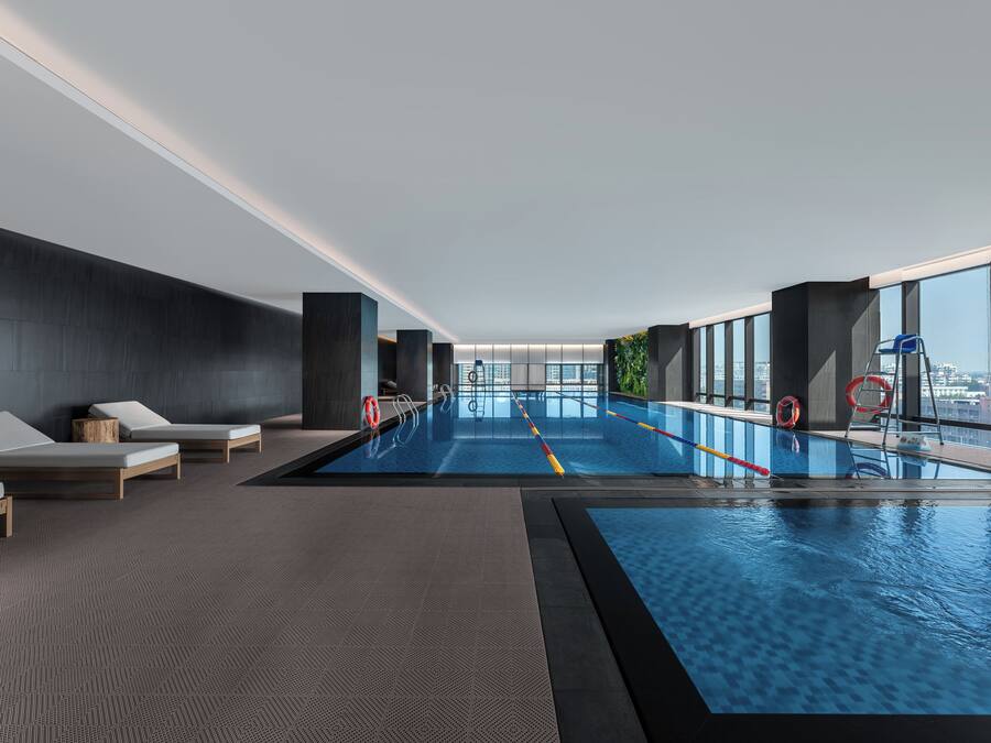 Una piscina interior moderna con sillones de descanso y vistas a la ciudad.