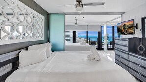A modern hotel room with a large bed, a ceiling fan, a TV, and a balcony with a city view. - Comfortable Beachside Condo with Pools & Gym Access 1404 (Miami Beach)