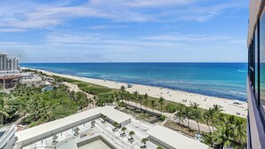 A beachfront hotel with a pool, palm trees, and a view of the ocean. - Comfortable Beachside Condo with Pools & Gym Access 1404 (Miami Beach)